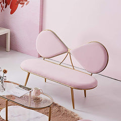 Pink bow-shaped bench in a room with a pink wall and glass coffee table.