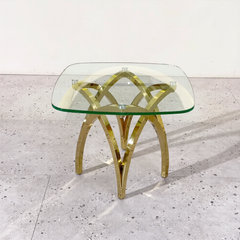 Glass table with gold metal legs on a light gray floor