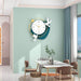 Decorative wall clock with birds on a light green wall in a modern dining room.