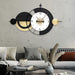 Decorative wall clock with black and gold design on a gray wall above a sofa.