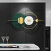 Modern wall clock with green and gold design on a black wall