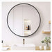 Round mirror with black frame in a bathroom setting
