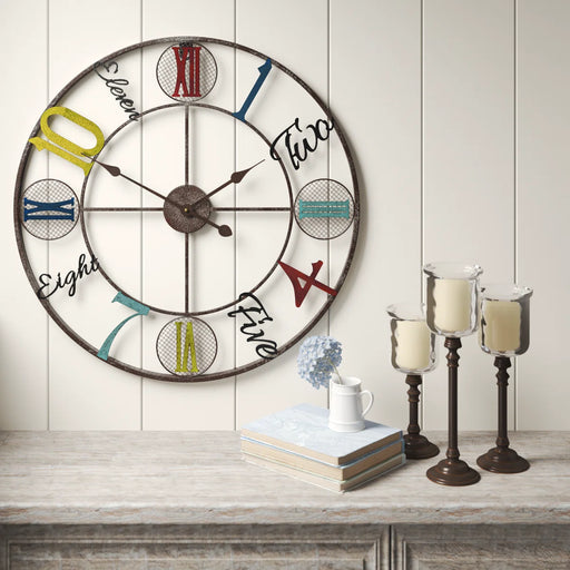 vintage wall clock with colorful numbers on a wooden surface with candles and books.