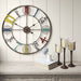 vintage wall clock with colorful numbers on a wooden surface with candles and books.