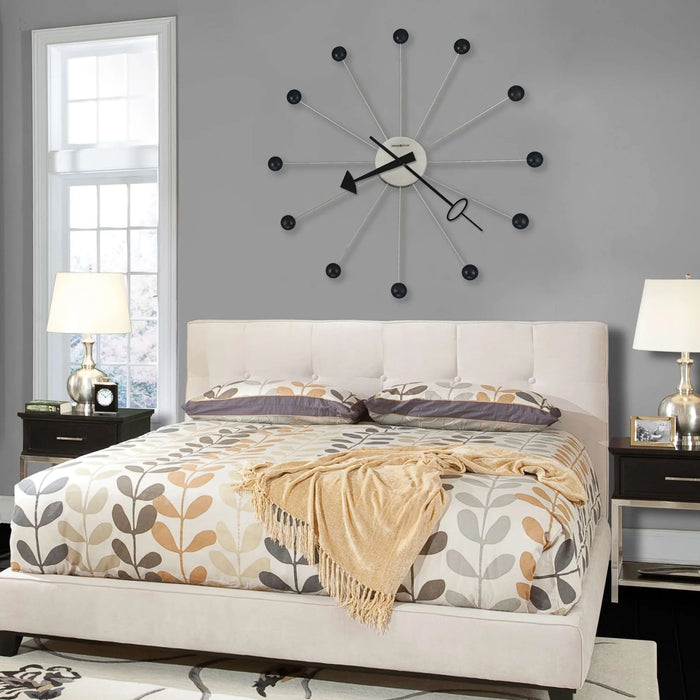 Bedroom with a large wall clock, bed, and nightstands.