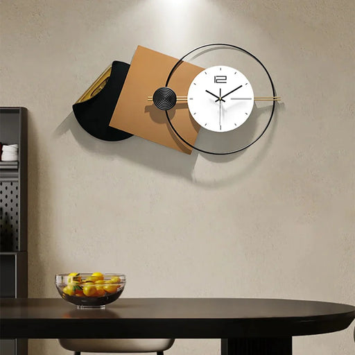 Modern wall clock with a minimalist design on a beige wall above a dark wooden table.