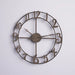 Bronze wall clock with Roman numerals on a light gray background