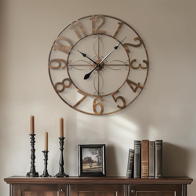 antique wall clock with candles and books on a wooden surface against a beige wall.
