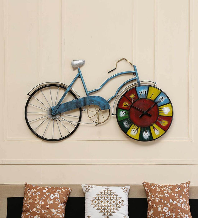 Decorative wall clock shaped like a bicycle with a colorful face on a beige wall.