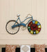 Decorative wall clock shaped like a bicycle with a colorful face on a beige wall.