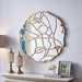 luxury wall mirror with gold leaf design on a white wall above a shelf.