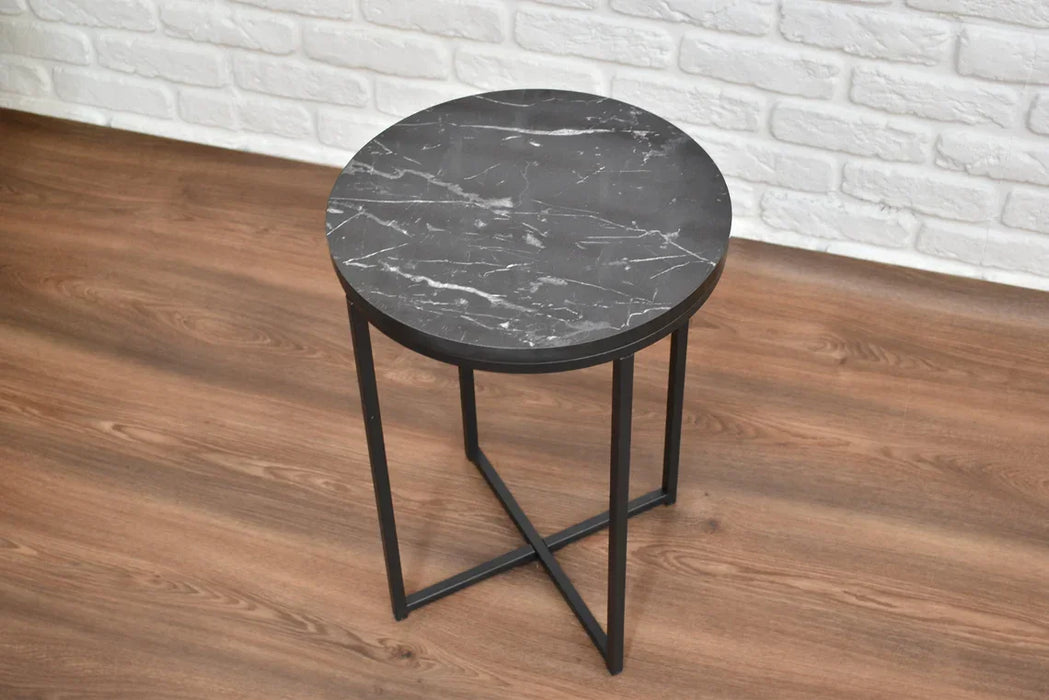 Round black marble bedside table with metal legs on a wooden floor.