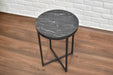 Round black marble bedside table with metal legs on a wooden floor.