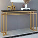 Console table with gold legs and black marble top against a gray wall.