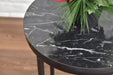 Round black marble table with a plant on a wooden floor