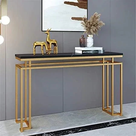 Console table with gold legs and black marble top in a room setting.