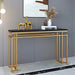 Console table with gold legs and black marble top in a room setting.