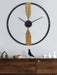 Decorative wall clock with gold accents on a white wall above a wooden console table.