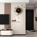 Modern wall clock with decorative text on a white wall in a living room setting.