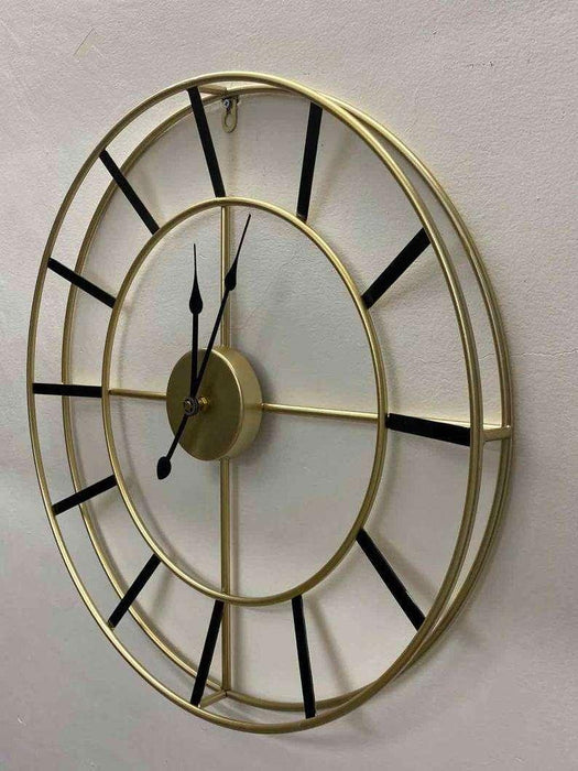 Decorative wall clock with gold frame and black hands on a light gray background