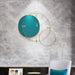 Teal wall clock with gold accents on a gray textured wall