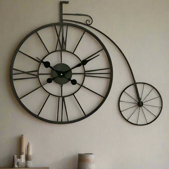 Decorative wall clock shaped like a vintage bicycle on a plain wall.