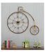 Decorative wall clock shaped like a vintage bicycle on a gray wall.