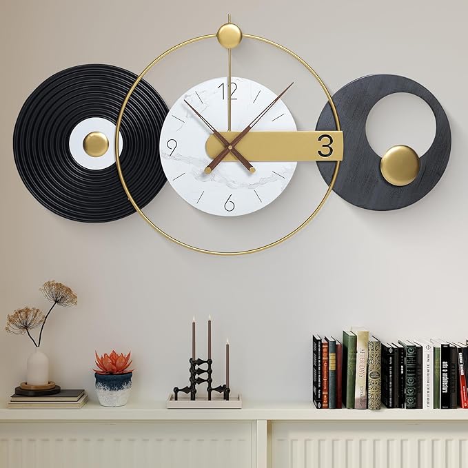Decorative wall clock with gold and black design on a wall with books and decor items below.