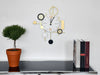 Modern wall clock with decorative elements on a shelf with a plant and books.