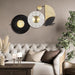 Decorative wall clock with black and gold design above a living room sofa.
