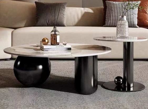 Modern coffee table with a marble top and black cylindrical base in a living room setting.