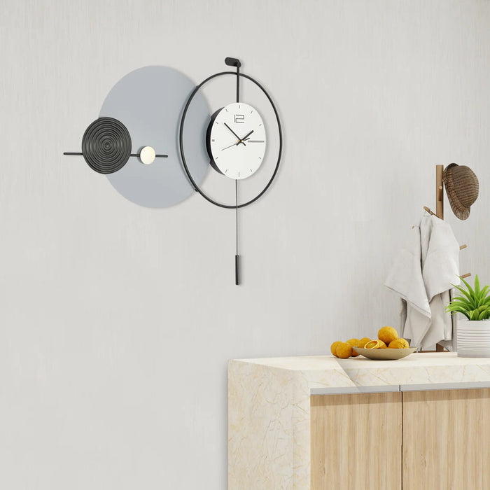 Modern wall clock with decorative elements on a light gray wall.