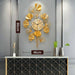 Decorative wall clock with gold leaf design on a gray wall.