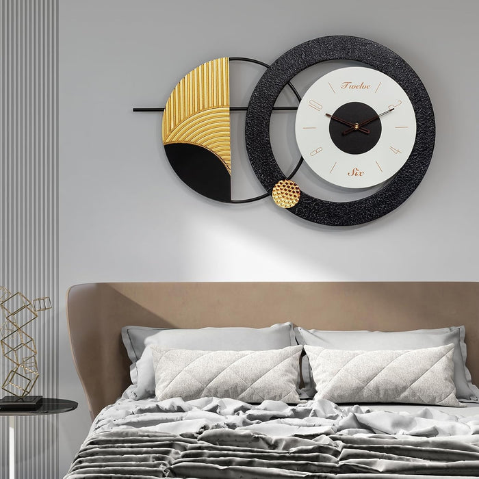 Decorative wall clock with gold and black design above a bed in a bedroom setting.