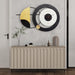 Decorative wall clock with geometric design on a wall above a cabinet.