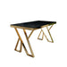 Modern table with black top and gold metal legs on a white background