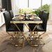 Dining table set with black chairs and gold legs in a modern interior setting.