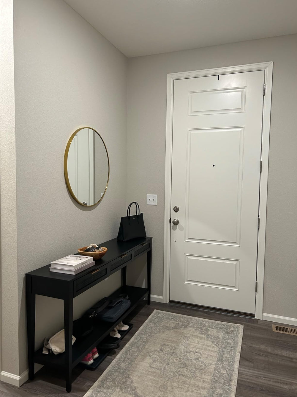 Entryway with a black console table, round mirror, and white door.