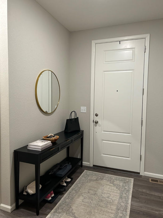 Entryway with a black console table, round mirror, and white door.