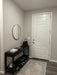 Entryway with a black console table, round mirror, and white door.