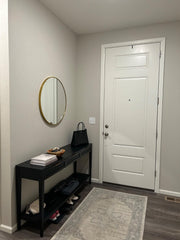 Entryway with a black console table, round mirror, and white door.