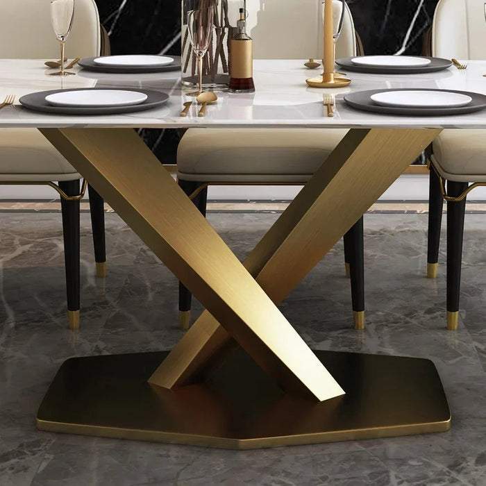 Dining table with marble top and gold metal base on a gray floor.