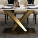 Dining table with marble top and gold metal base on a gray floor.