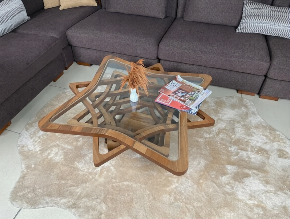 Wooden star-shaped coffee table in a living room with a gray sectional sofa and decorative items.