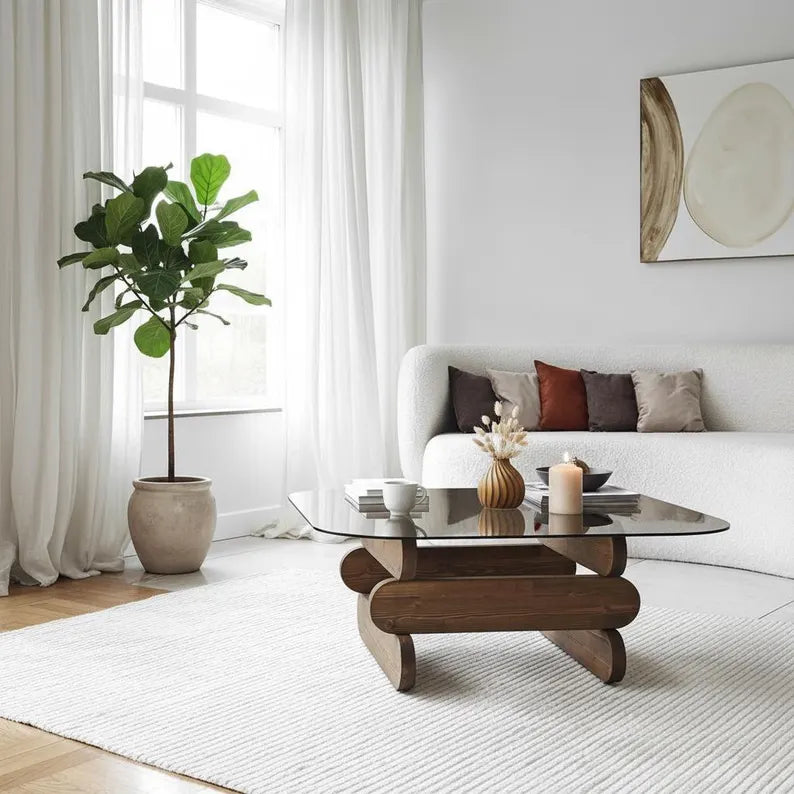 Modern living room with a glass coffee table, white sofa, and decorative elements.