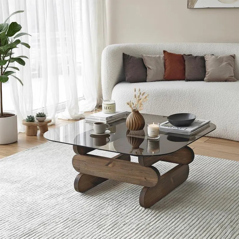 Modern living room with a glass coffee table, white sofa, and decorative items.
