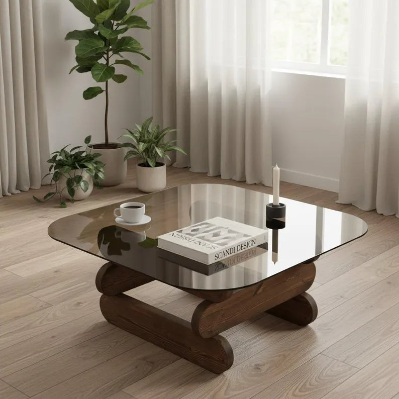 Glass coffee table with wooden base in a room with plants and curtains