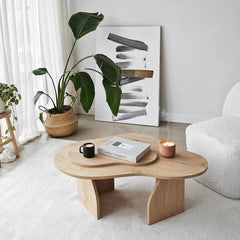 Modern living room with a wooden coffee table, plant, and abstract art.