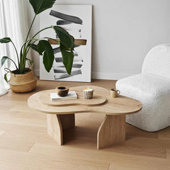 Wooden coffee table in a living room with a plant, artwork, and a chair.