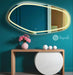 irregular mirror with LED lighting on a teal wall above a wooden console table.